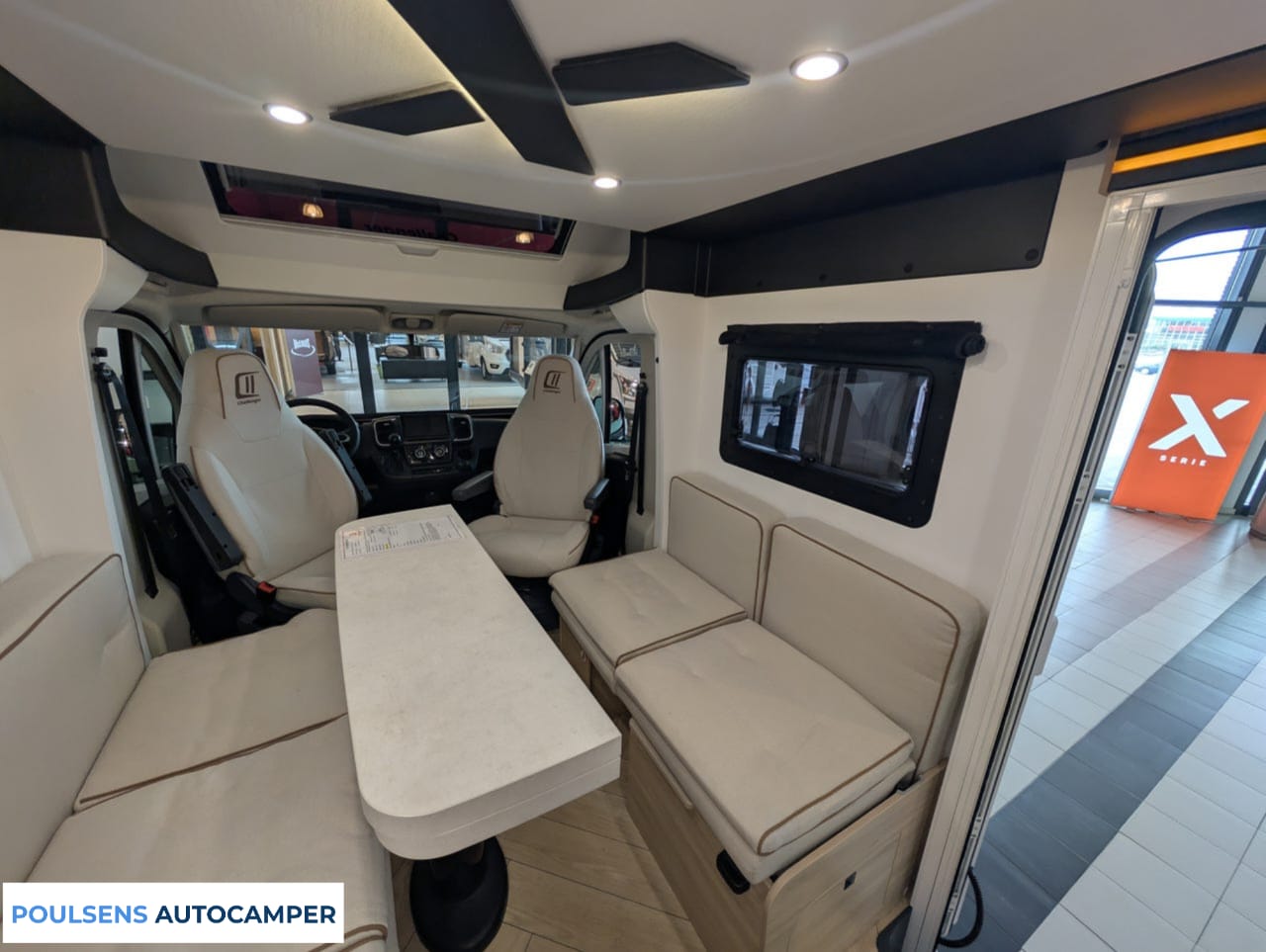 Salon intérieur du camping-car compact Challenger X150 2025 avec banquettes confortables et table centrale